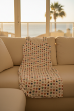 Colorful star-patterned blanket draped over a beige sofa with a scenic background