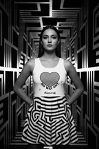Woman wearing a tank top with a heart design and text in a black and white geometric patterned room.
