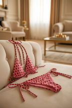 Pink polka dot bikini set on a beige sofa in a living room setting