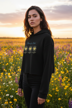 Woman wearing a black hoodie with floral designs in a field of flowers at sunset